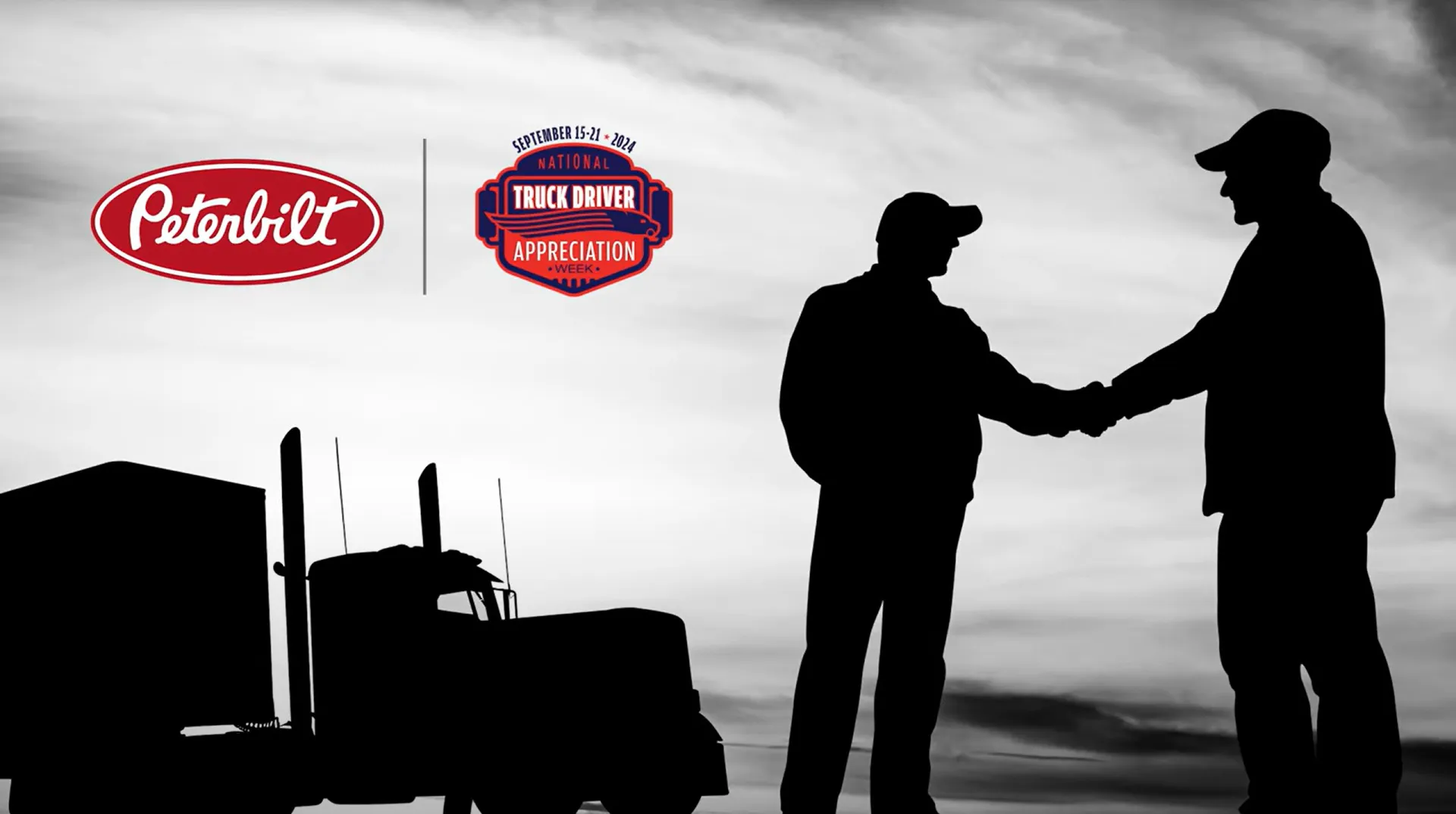 Silhouette of truck drivers shaking hands in front of truck in background