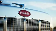 Close-up Image of Peterbilt Model 589 On-Highway Hood with Red Oval Logo Over Grille - Thumbnail